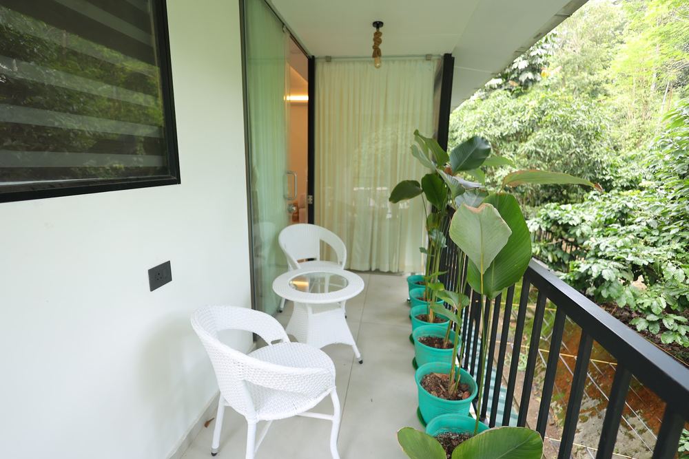 Balcony with wicker chairs looking onto the plantation canopy
