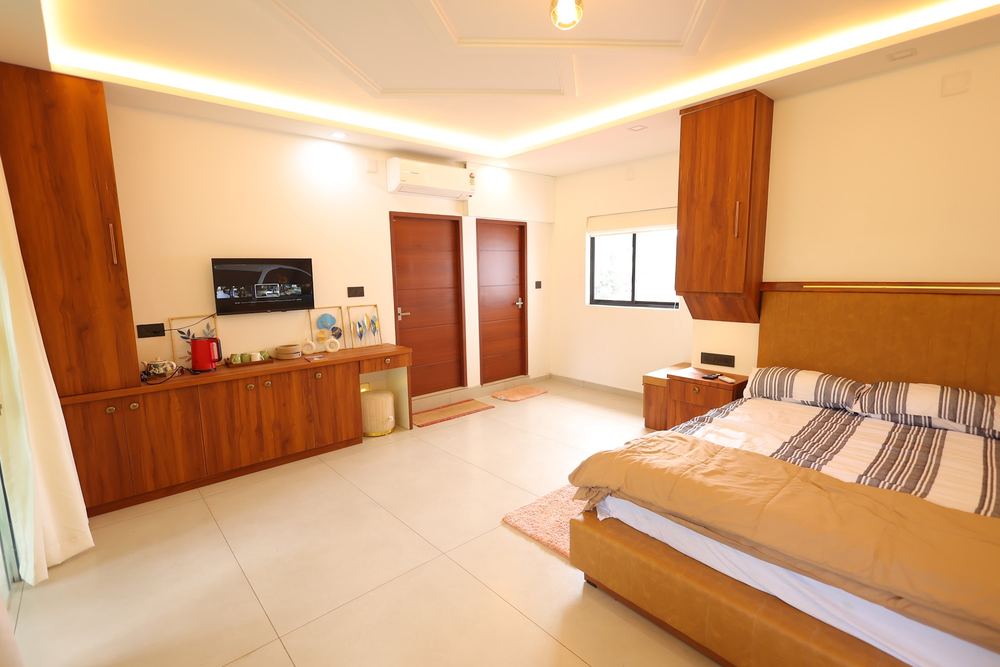 King bed, wardrobe and wall-mounted TV in a bright room