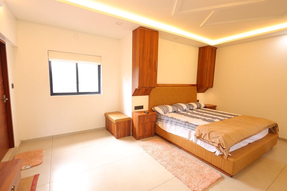 Bed with a leather headboard and a storage bench by the window