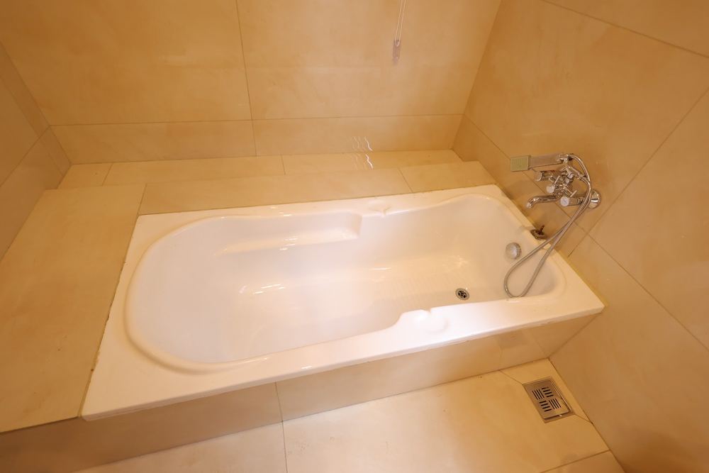 A deep soaking tub below a shuttered window