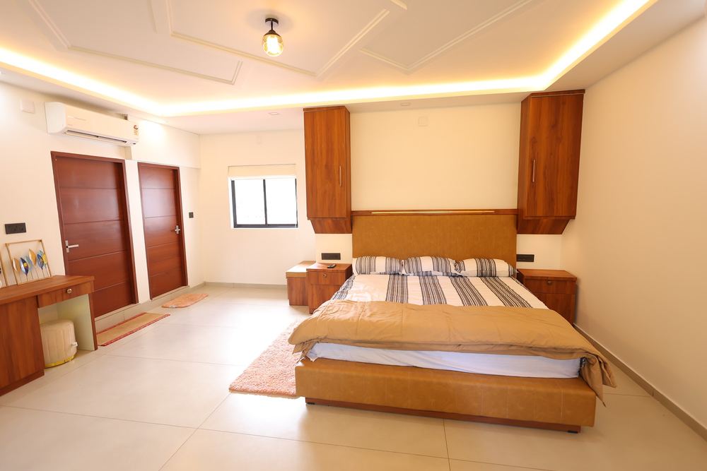 Bed with striped linen and wooden cabinetry, window onto garden
