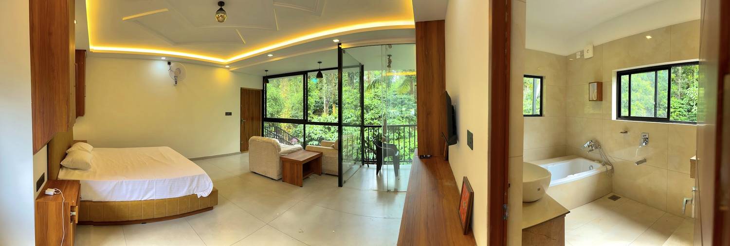 Panorama of the full suite: bed, sitting area, balcony and bathroom