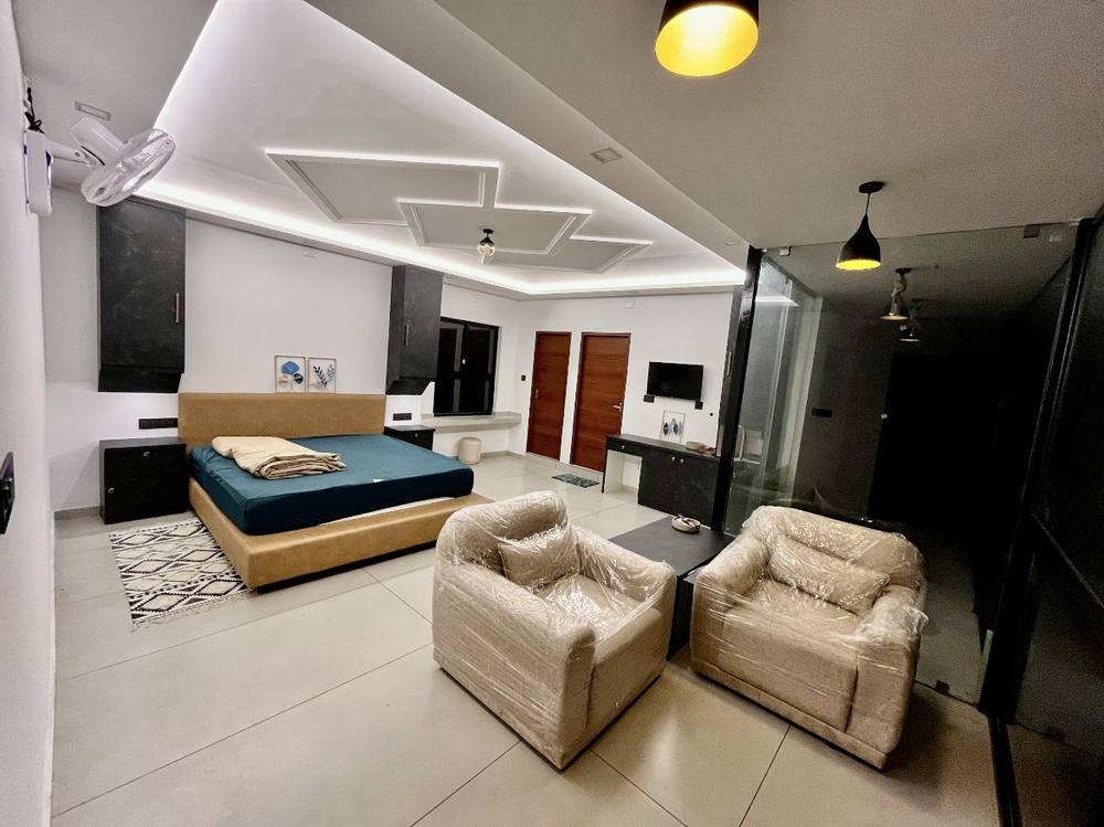 Room at night, warm cove lighting, glass wall to the dark plantation