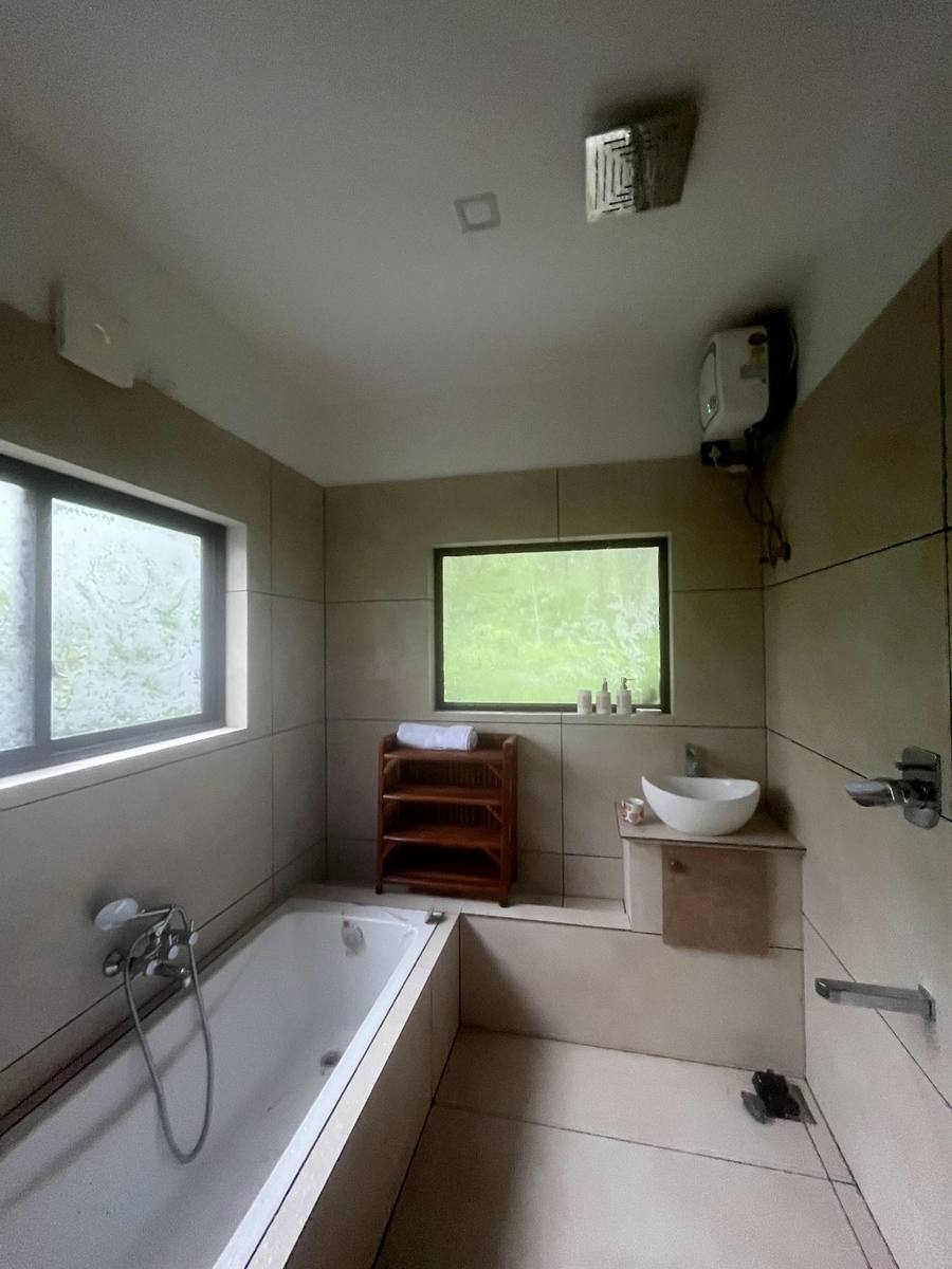 Bathroom with a tub and a window onto green